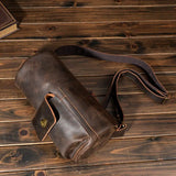 テーブルに置かれたダークブラウンのクレイジーホースレザー クロスボディバッグ。耐久性と収納力に優れた本革製。