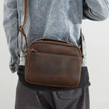 ミニショルダーバッグM-クレイジーホースレザーバッグを肩掛けした男性。ヴィンテージ感あるダークブラウンの牛革が魅力。